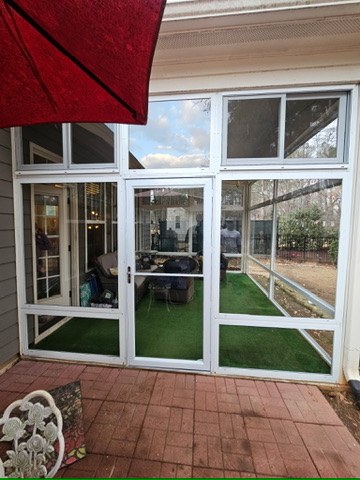 Exterior view of a white enclosure door integrated into a CWS clear acrylic porch enclosure.