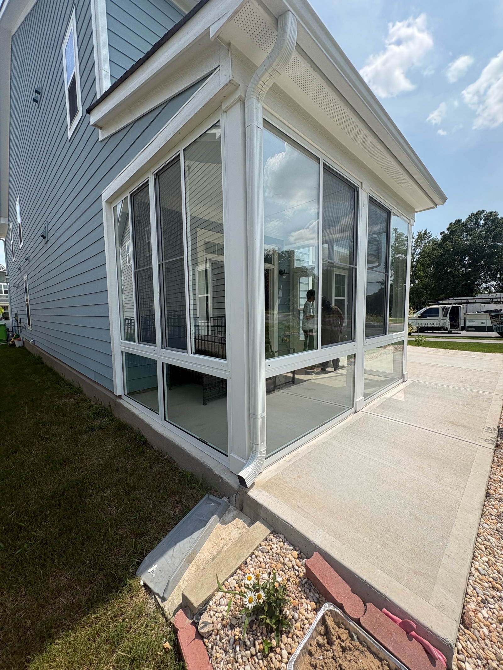 Corner exterior view of a white CWS porch enclosure with single-pane clear glass.
