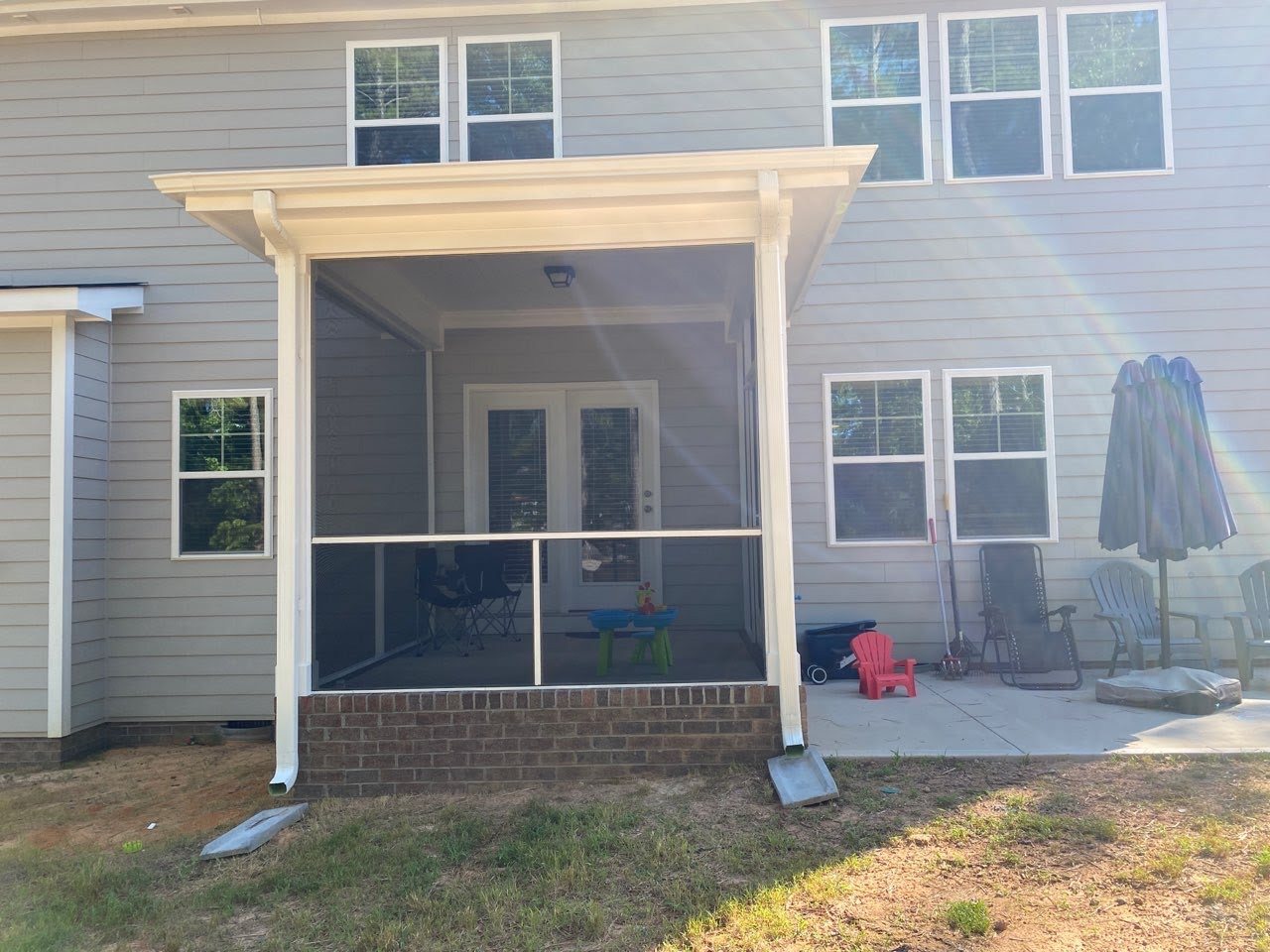 White extruded-aluminum screen enclosure fitted to a covered backyard porch.