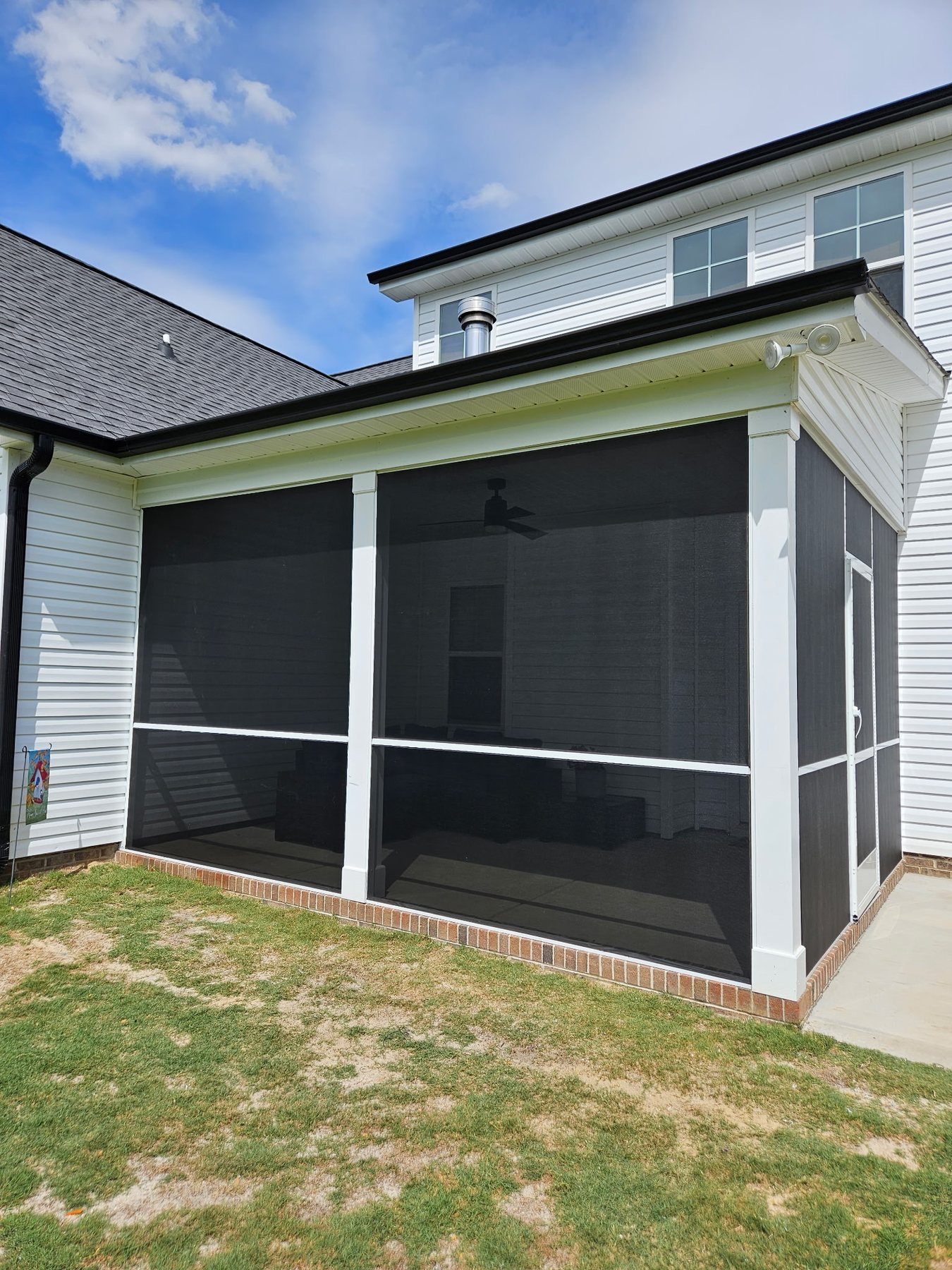 Completed extruded-aluminum porch enclosure with dark screen mesh and white framing.