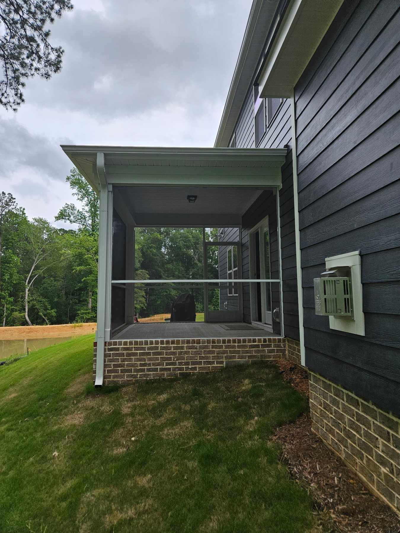 Completed dark-screen enclosure on a covered side porch with white aluminum framing.