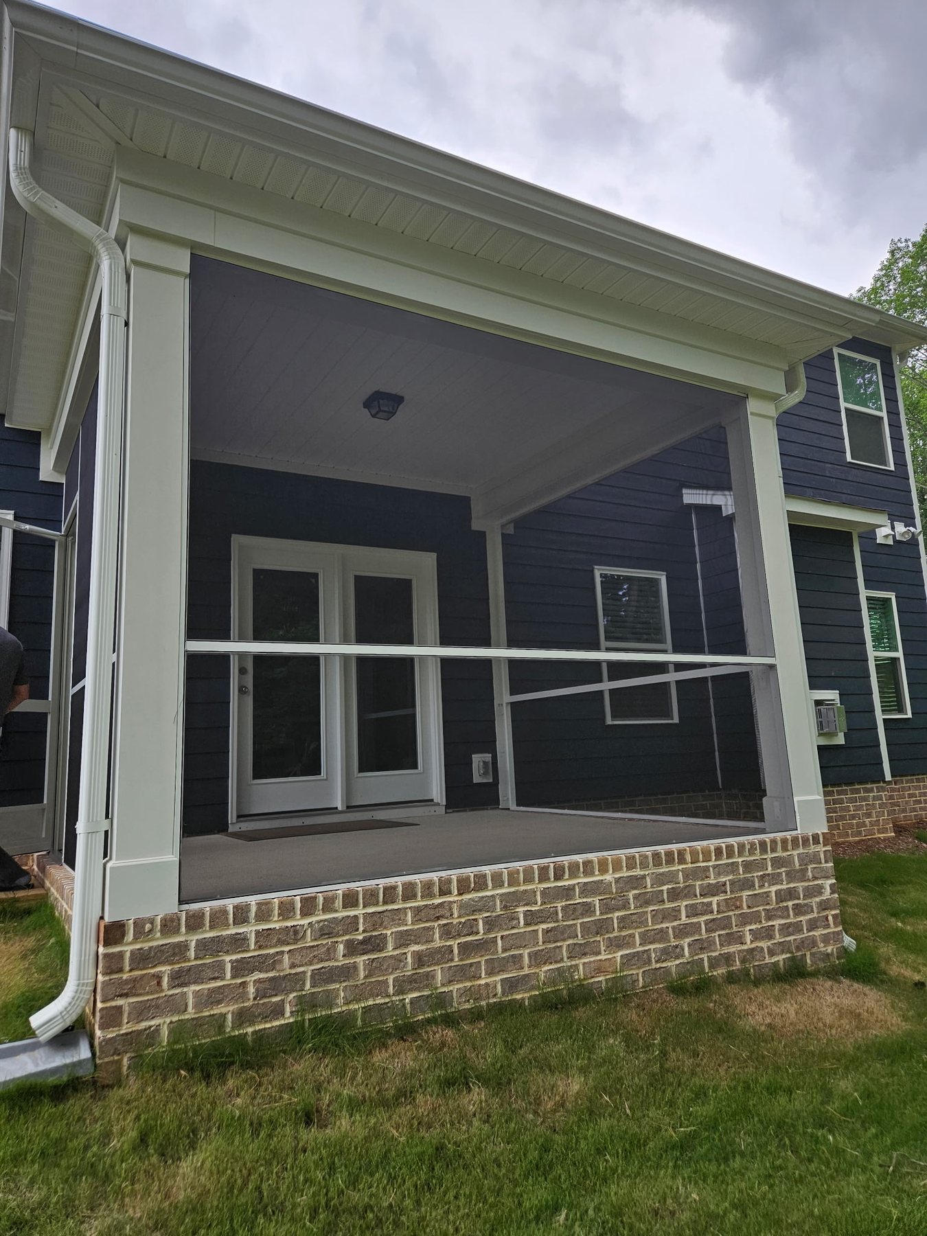 Completed white extruded-aluminum porch enclosure with a screened entry door.