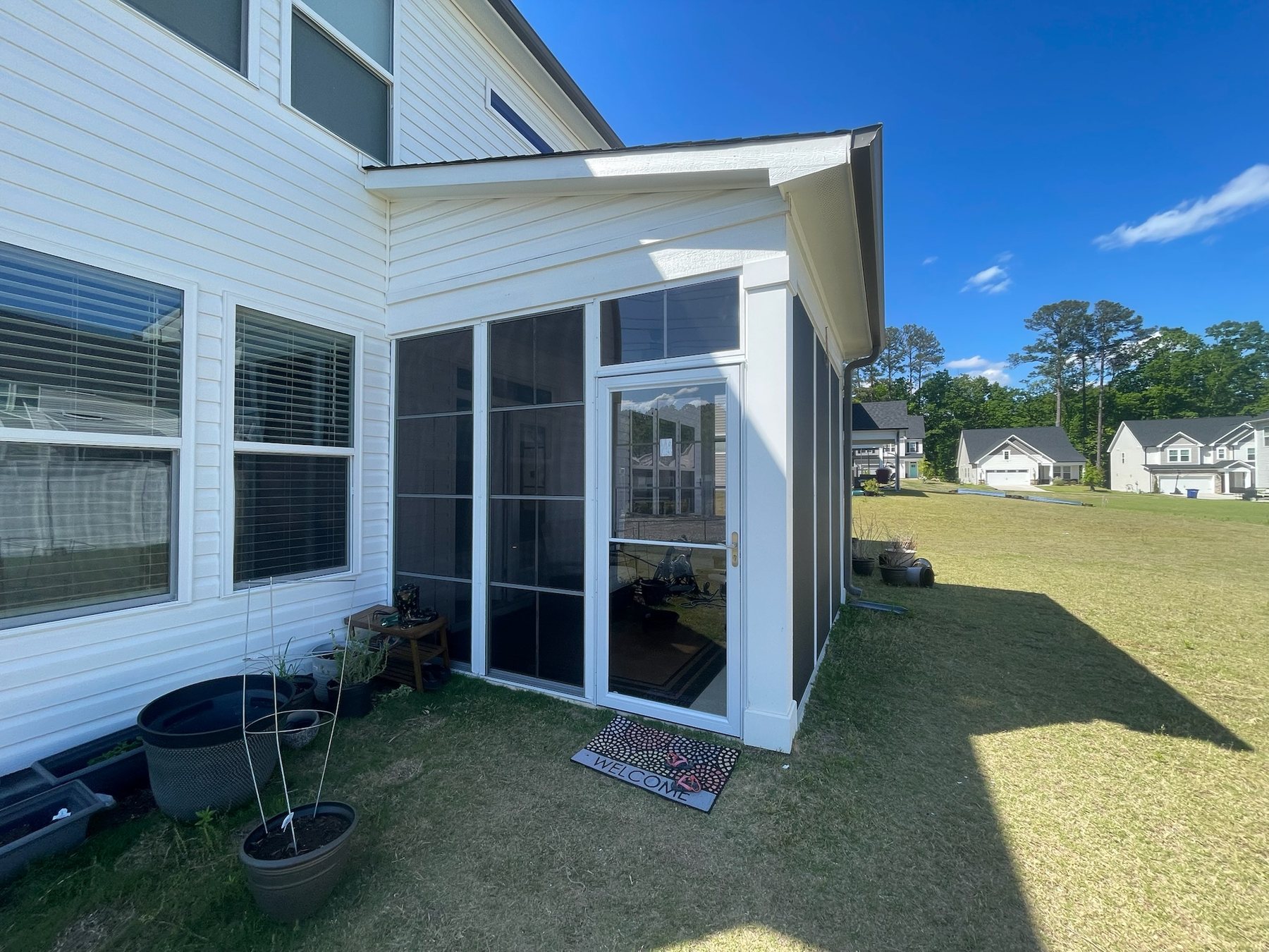 White self-storing storm door installed at a completed porch enclosure.
