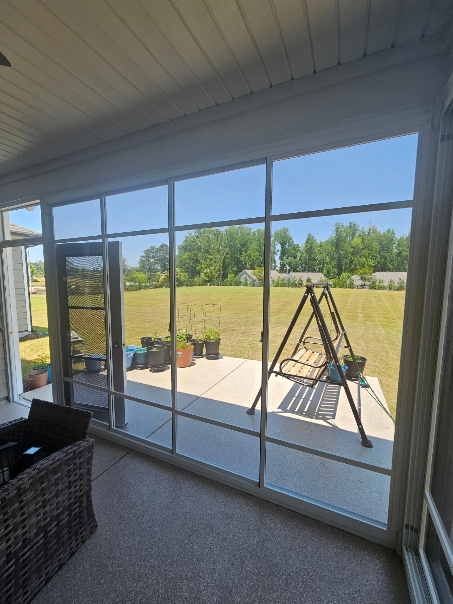 Interior view through a floor-to-ceiling Eze-Breeze porch enclosure with two horizontal spreader bars.