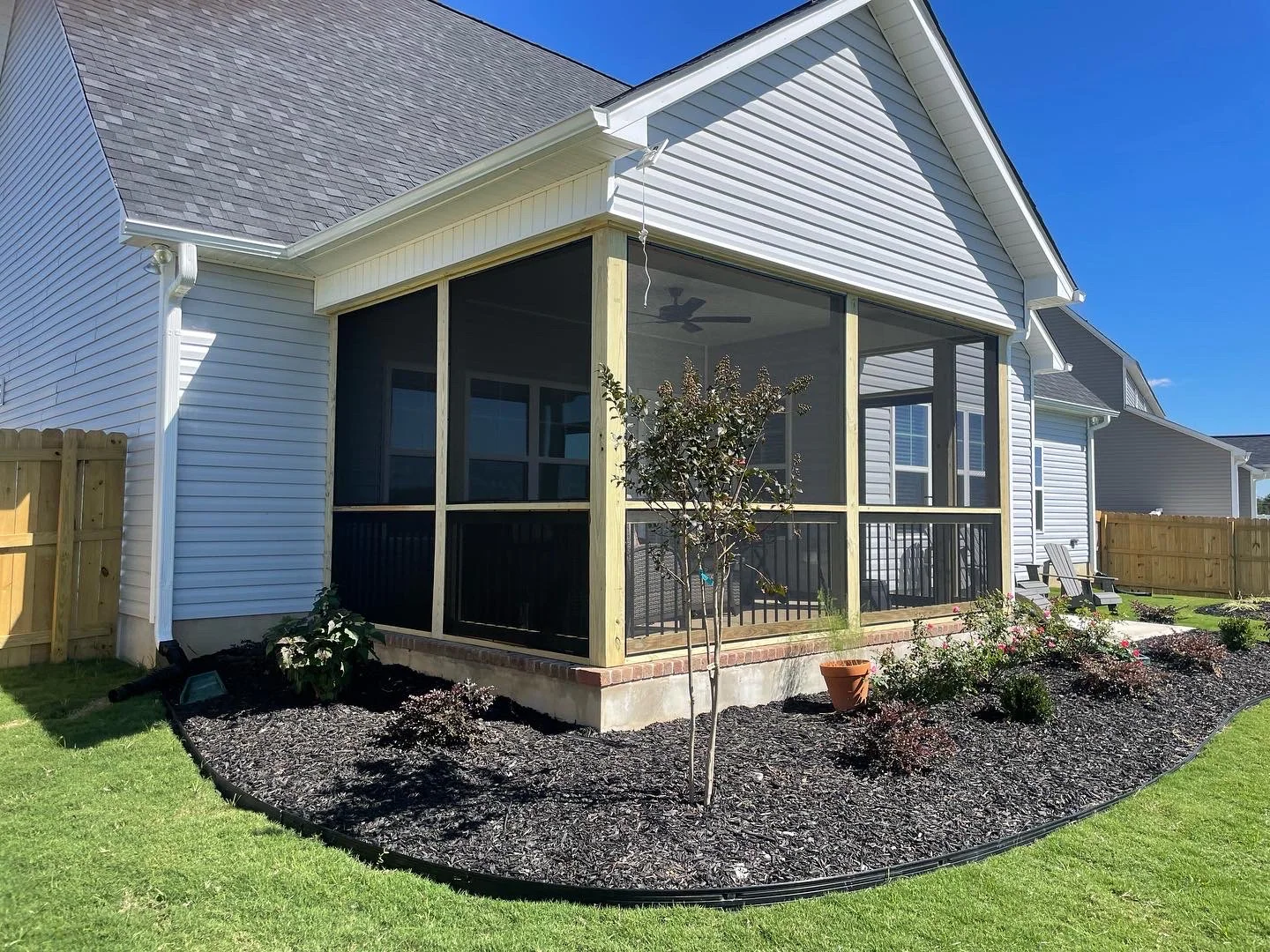 Two sides of a wood porch fitted with black removable screen panels.