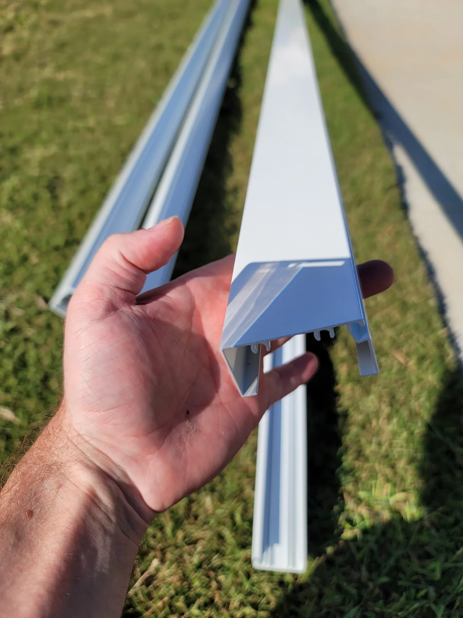 End and length view of a white 1-by-2 extruded-aluminum enclosure member.