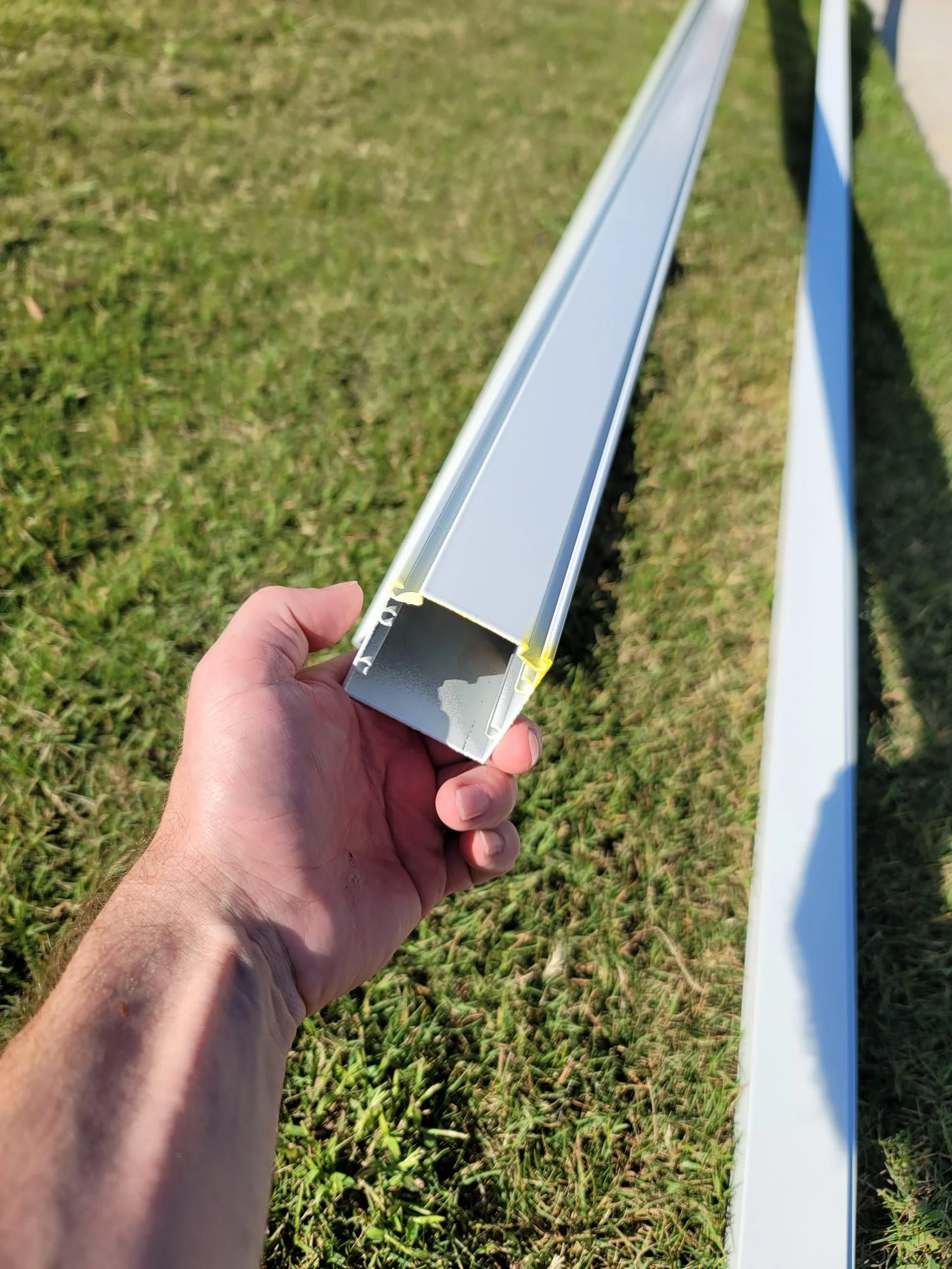 End and length view of a white 2-by-2 extruded-aluminum enclosure member.