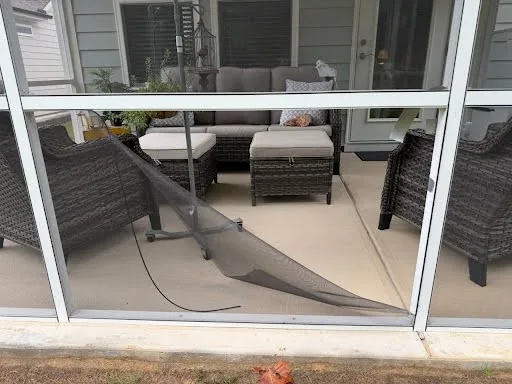 Damaged screen mesh visible in a porch opening.