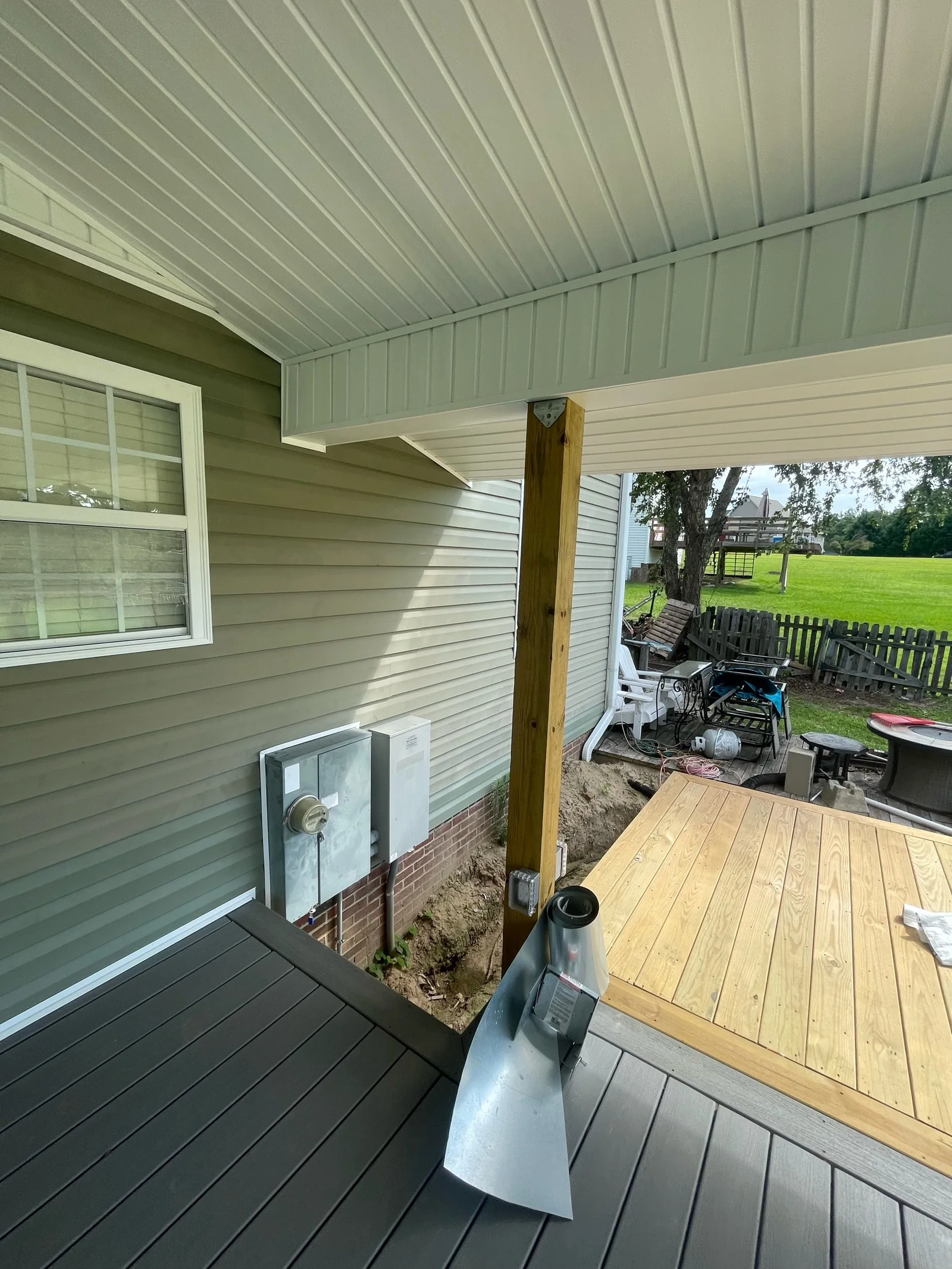 Interior porch view before a screen system is installed, showing a support post, deck transition, wall-mounted equipment and ceiling details.