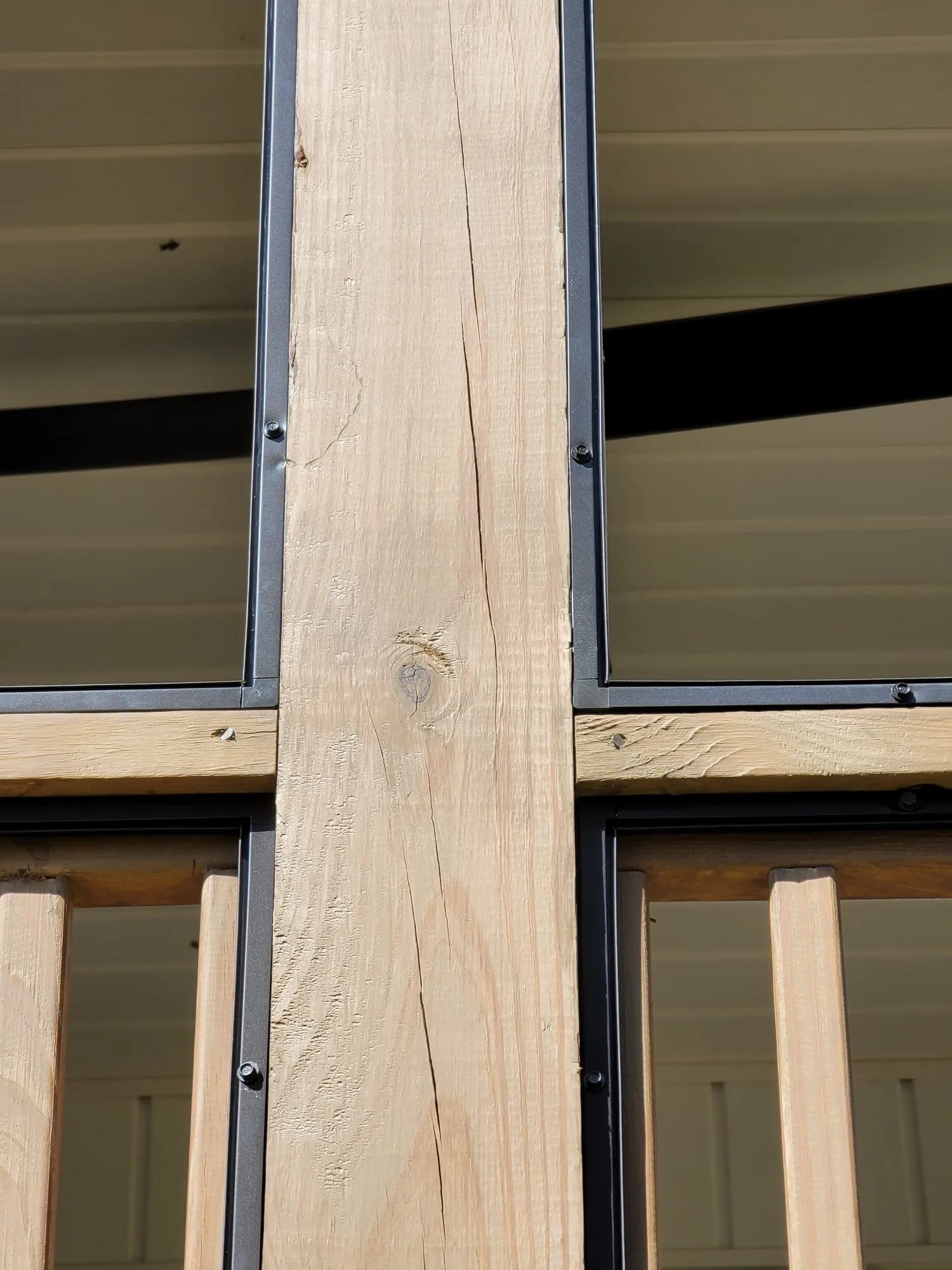 Black removable screen panels fastened around a wood porch post and rail.