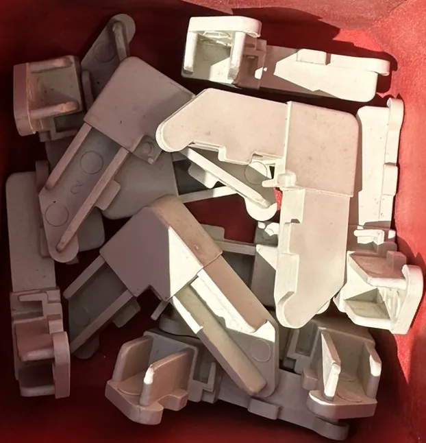 White plastic corner keys used inside roll-formed aluminum window-screen frames.