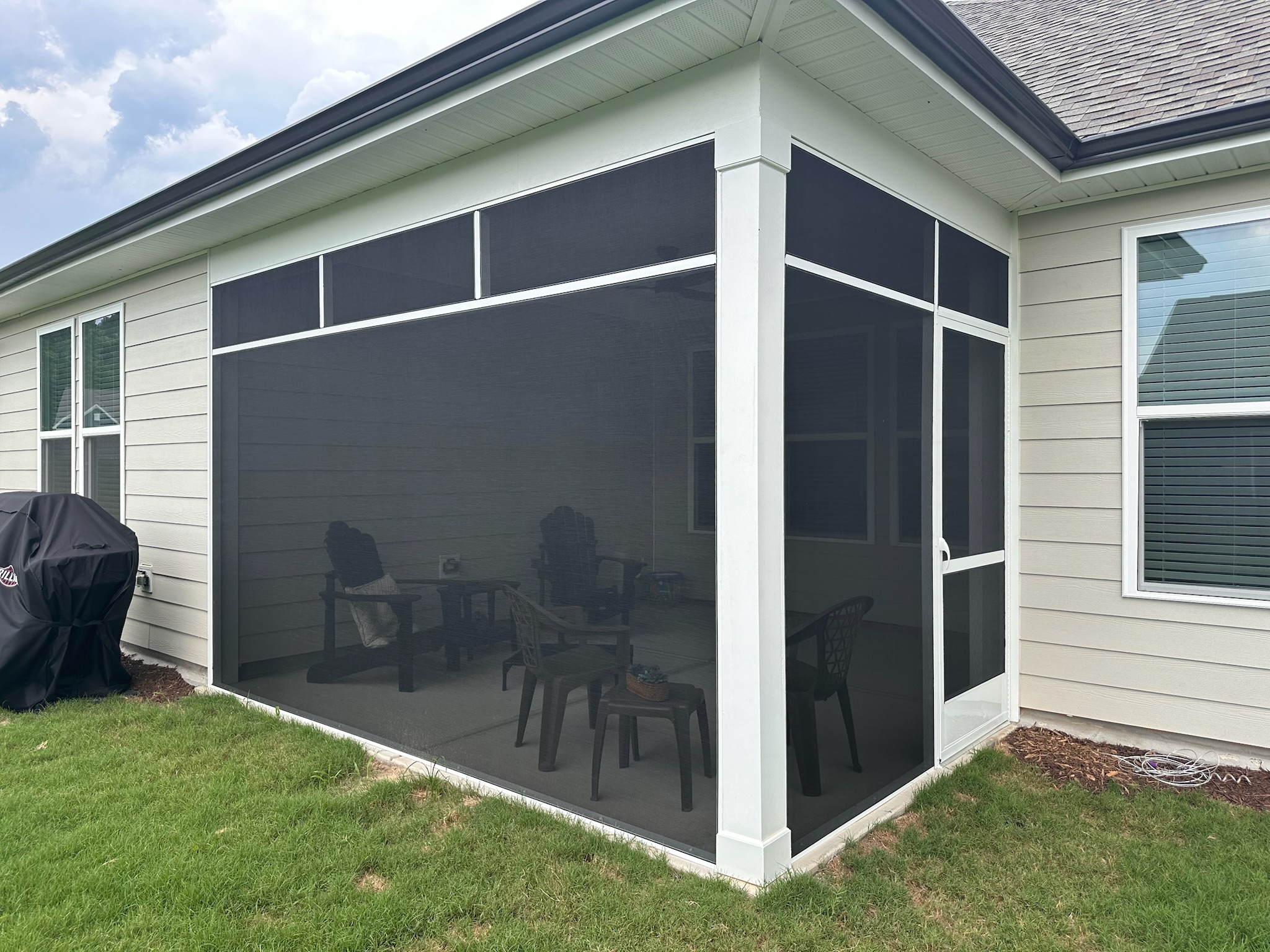 White extruded-aluminum screen porch with a door-header transom continuing around the enclosure.