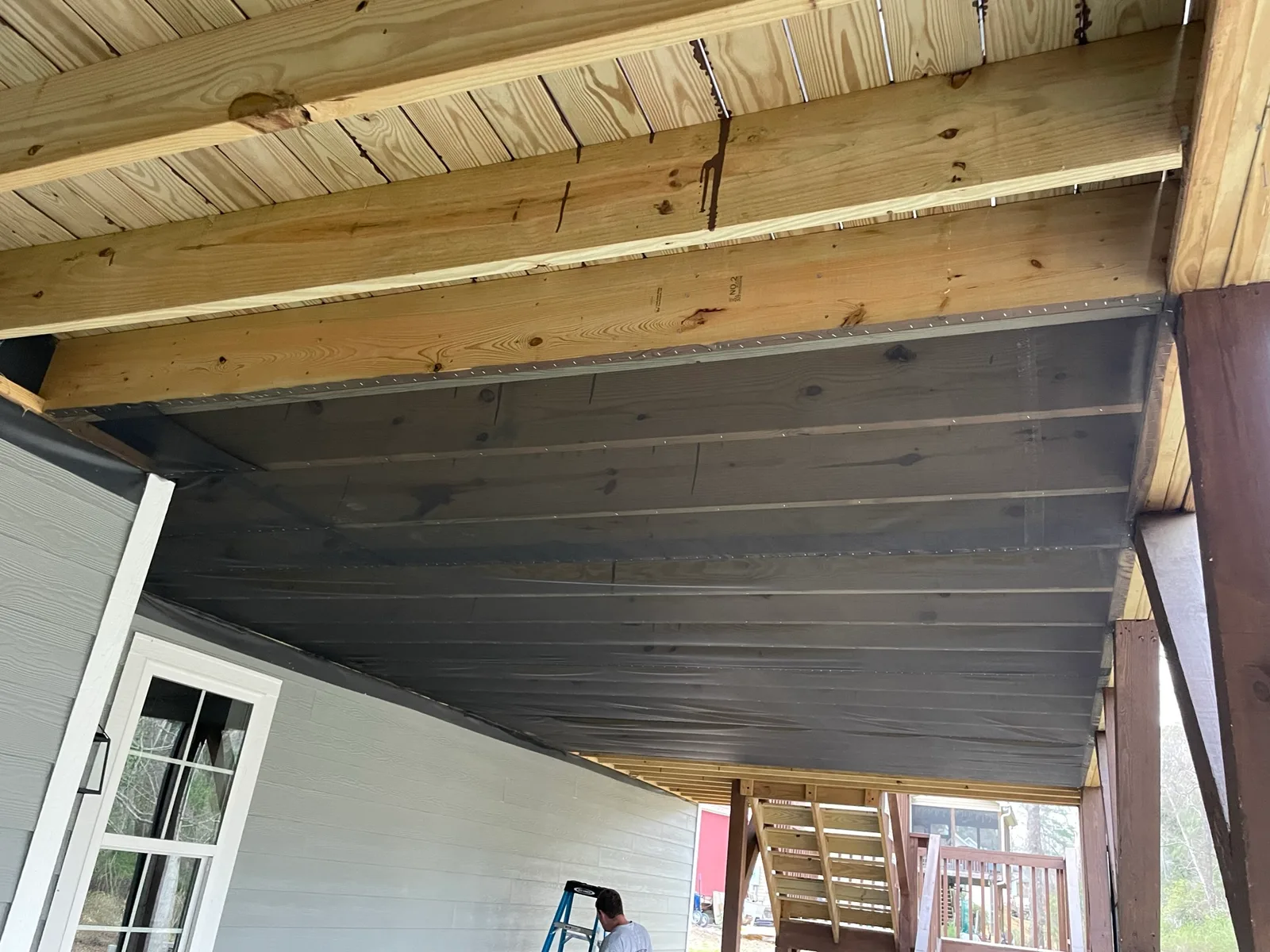 Finished screen mesh installation beneath long porch joist bays.