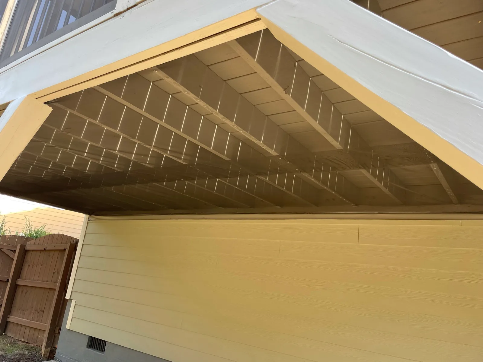 Screen mesh installed beneath porch joists at a gable-shaped end.